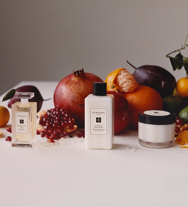 Jo Malone London Lime basil and mandarin bath oil, pom noir body lotion and creme surrounded with mandarins and pomegranates