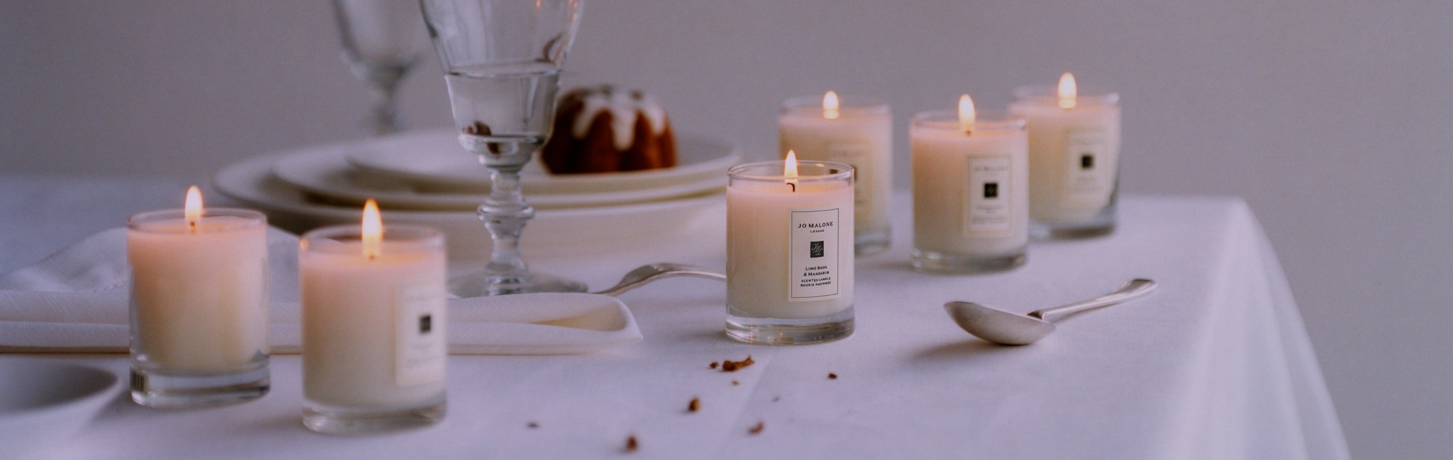 six travel sized candles scattered across a dining table